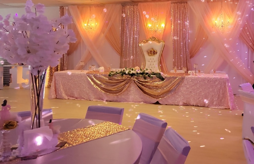 Elegantly decorated quinceañera venue with pink and gold lighting